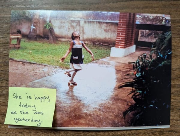 Diliny as as child dances in the rain in her grandmother’s garden. A post-it stuck to the photo reads: She is happy today as